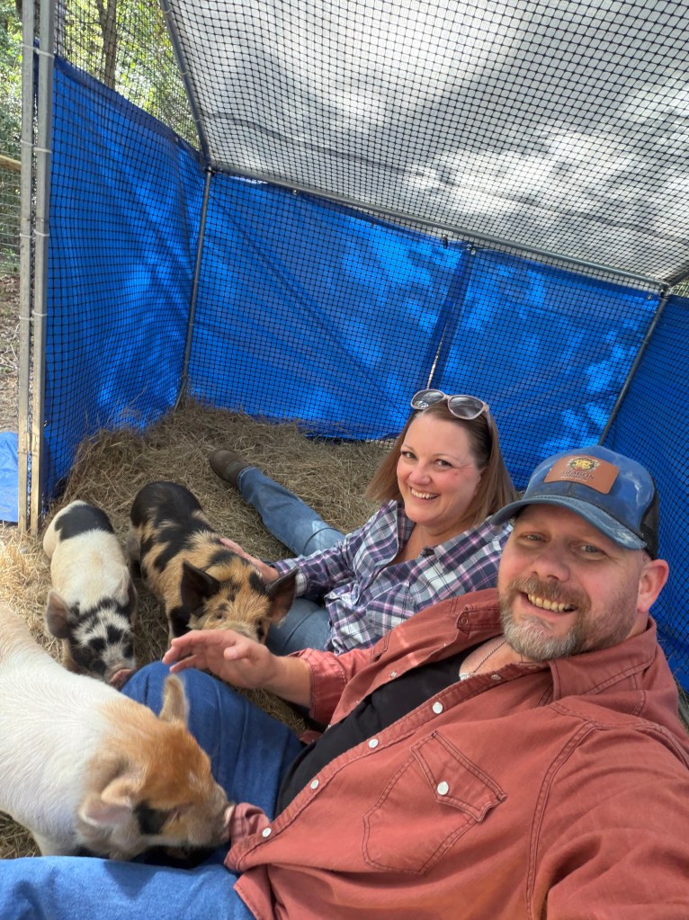 Husband and wife spending time together with their Kunekune pigs at Aragon Acres in East Texas.